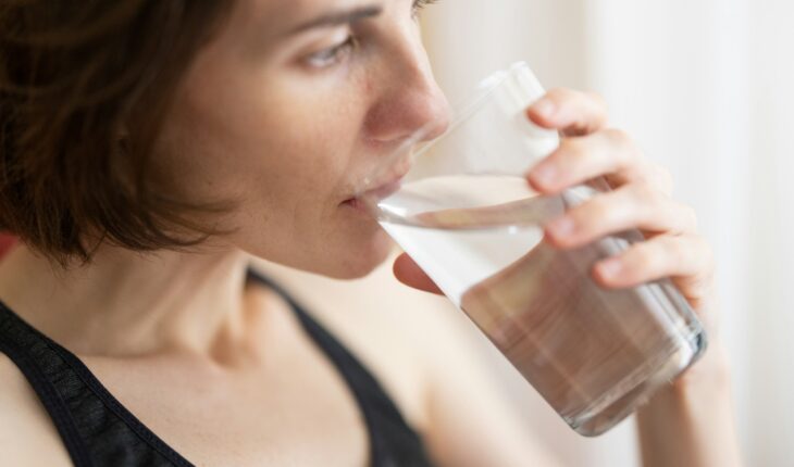 woman in black tank top drinking water