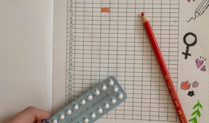 Creative period tracker notebook with a hand holding birth control pills.