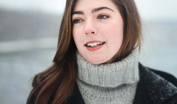 Close-up portrait of a young woman smiling outdoors in the snowy winter.