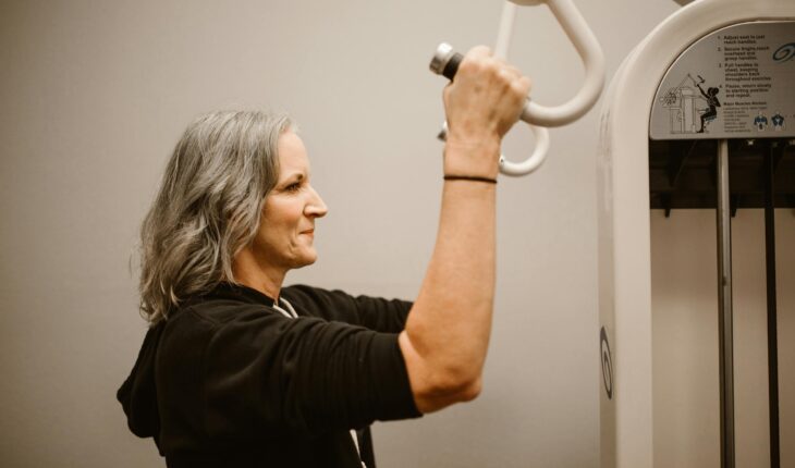 Active senior woman working out on gym equipment, focusing on strength and wellness.