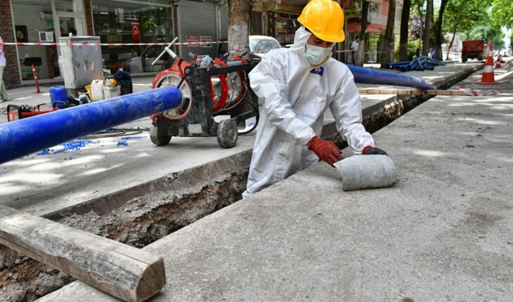 a man wearing a protective suit and a hard hat working on a street