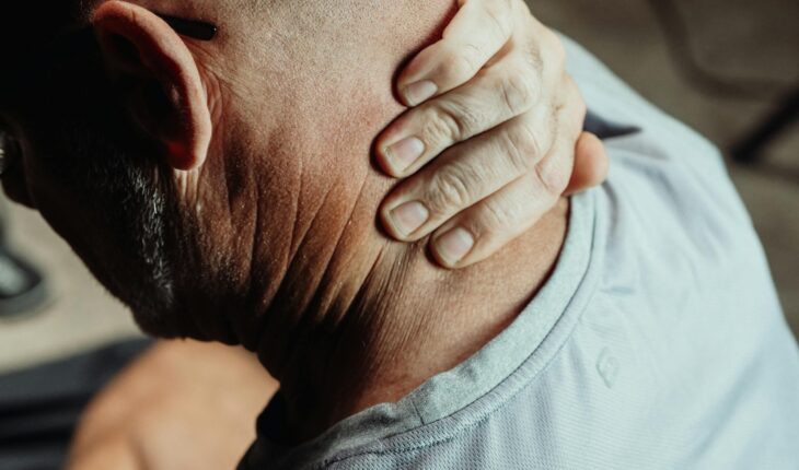 Man with neck pain holding his neck in discomfort, conveying tension or stress.