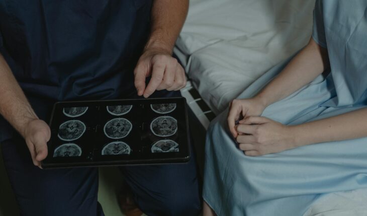 A doctor shows and explains brain scan images to a patient in a medical setting.