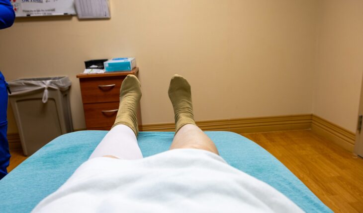 Patient rests on a bed with legs in bandages.